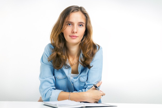 Portrait de la jeune fille moderne est l'étudiant assis à l'intérieur sur fond blanc