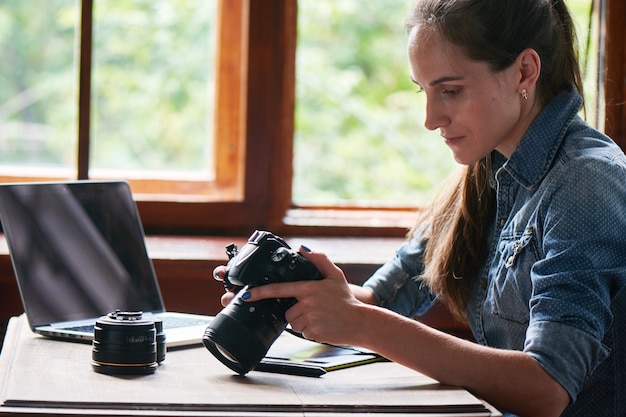 Portrait d'une jeune fille photographe travaillant avec un ordinateur