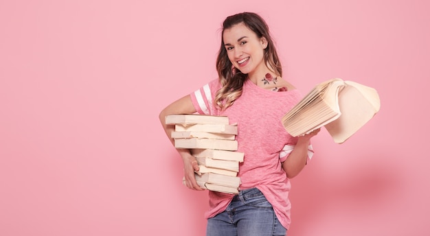 Portrait D'une Jeune Fille Avec Une Pile De Livres Sur Un Mur Rose