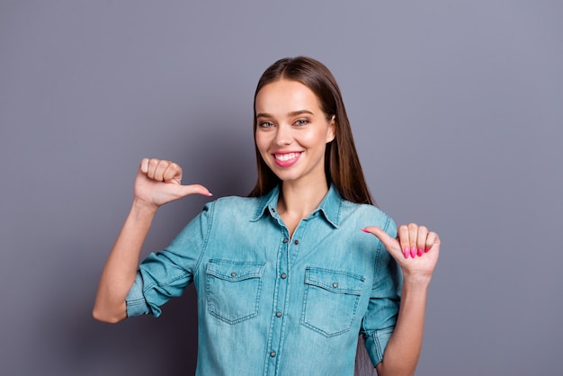 Portrait de jeune fille posant contre un mur gris