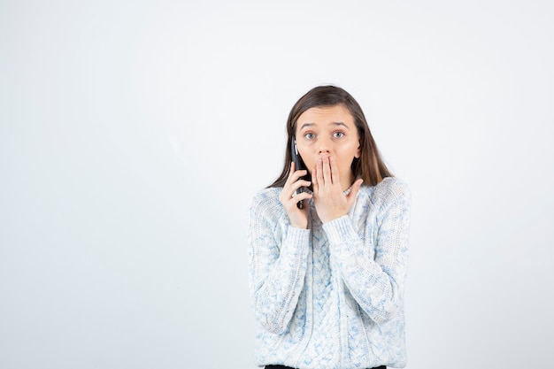 Portrait de jeune fille en pull en laine, parler avec quelqu'un sur téléphone portable.