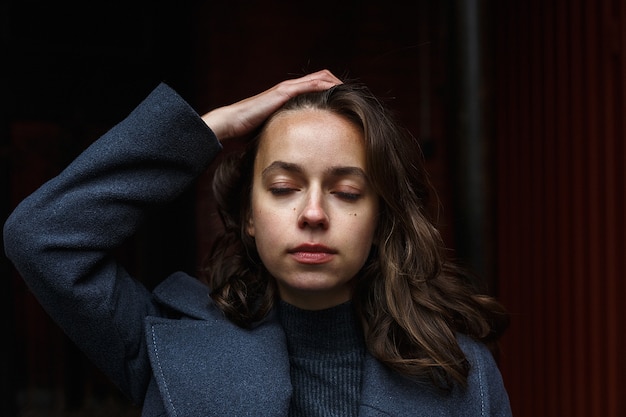 Portrait de jeune fille réfléchie en manteau gris et col roulé posant à l'extérieur