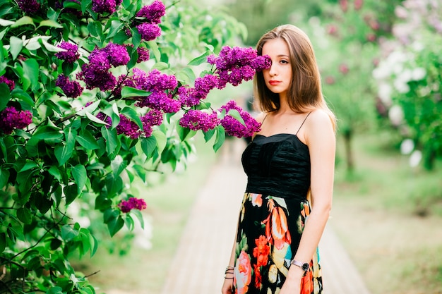 Portrait de jeune fille sensuelle aux cheveux longs, appréciant anf relaxant dans le parc fleuri de printemps.