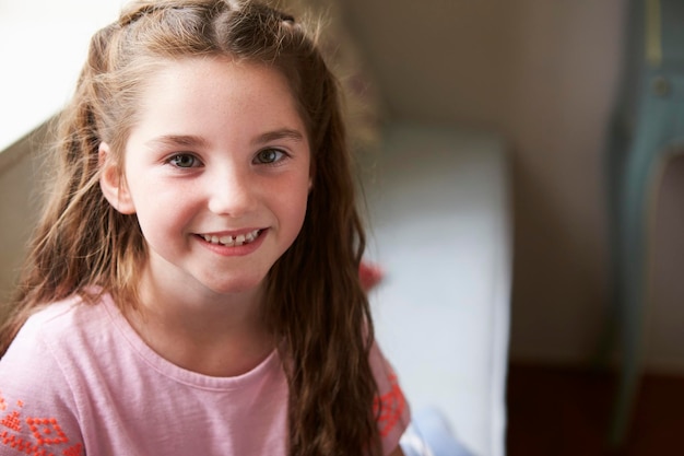 Portrait de jeune fille souriante assise sur un siège de fenêtre à la maison