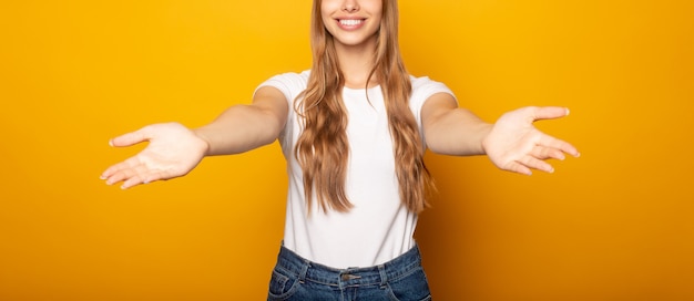 Portrait de jeune fille souriante à bras ouverts isolé sur jaune