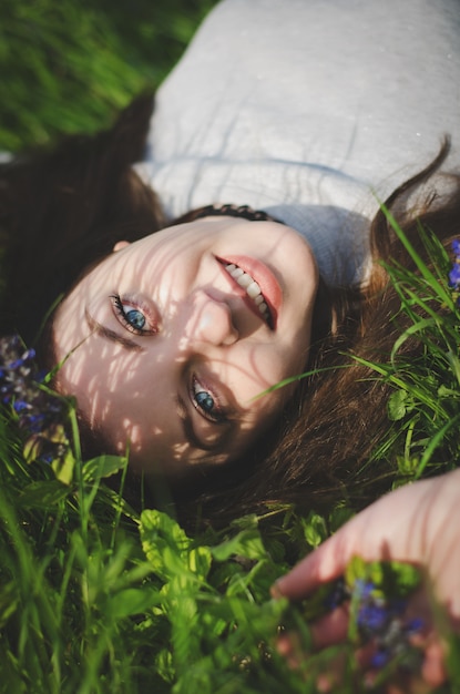 Photo portrait de jeune fille souriante, couché sur l'herbe dans le jardin. image tonique.