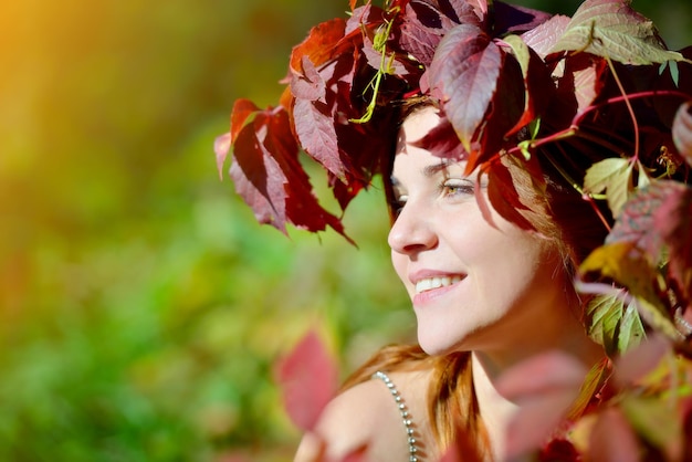 Portrait d'une jeune fille souriante avec une couronne de feuilles d'automne sur la tête