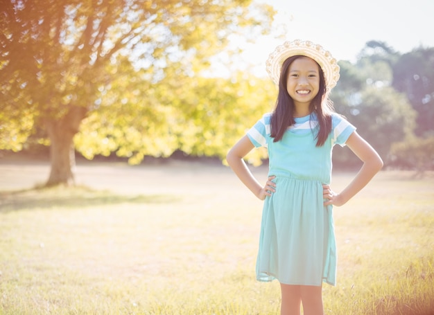 Portrait de jeune fille souriante debout avec la main sur la hanche dans le parc