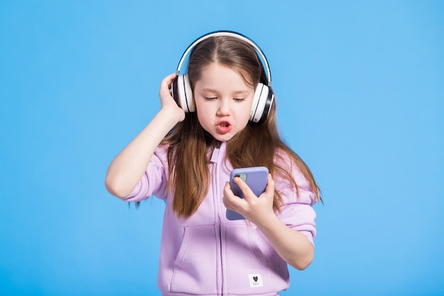 Portrait d'une jeune fille souriante qui chante et écoute de la musique avec des écouteurs sans fil