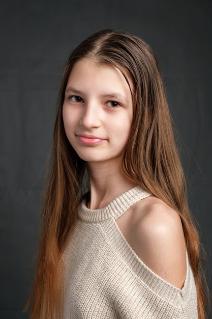 Portrait de jeune fille souriante et regardant à l'avant sur fond gris