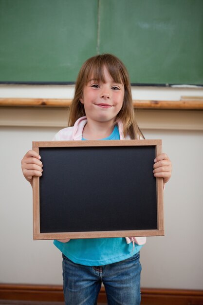 Portrait d&#39;une jeune fille souriante tenant une ardoise scolaire