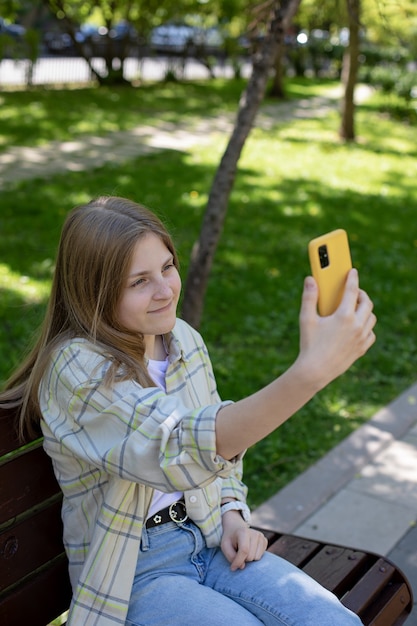 Portrait d'une jeune fille souriante tenant un smartphone prenant des selfies ayant un appel vidéo avec des amis