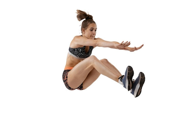 Portrait de jeune fille sportive en formation de vêtements de sport sautant isolé sur fond de studio blanc