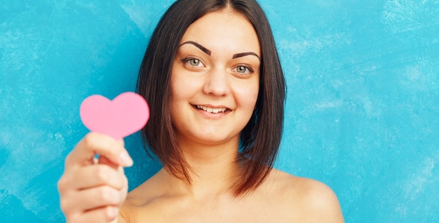 Portrait de jeune fille tenant coeur de papier rose.