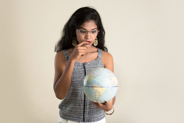 Portrait de jeune fille tenant et posant avec un globe terrestre.