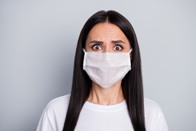 Portrait de jeune fille terrifiée choquée entendre la terrible épidémie de virus corona propagation nouvelles porter un masque médical tshirt blanc isolé sur fond de couleur grise