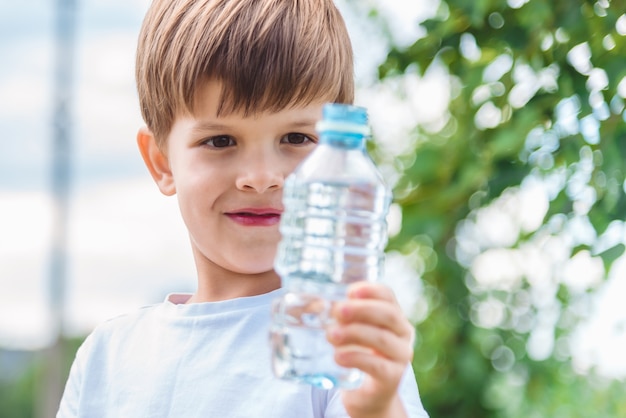 portrait jeune garçon avec une bouteille d'eau