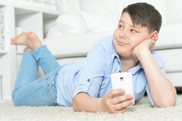 Portrait de jeune garçon avec smartphone à la maison