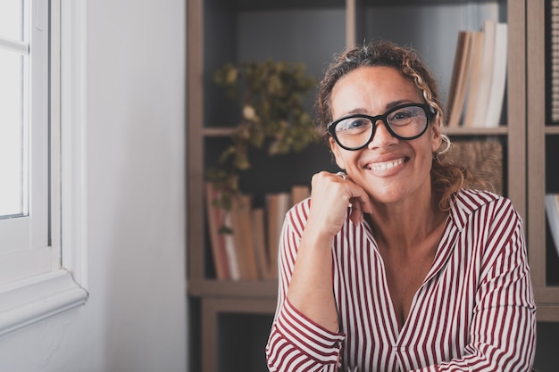 Portrait d'une jeune et heureuse femme joyeuse souriante en regardant la caméra en s'amusant. Tête d'une femme travaillant à domicile au bureau.