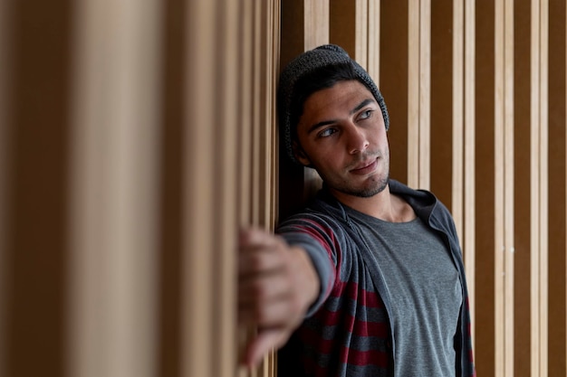 Portrait de jeune homme 22 hipster latino-américain avec une attitude détendue Fond en bois Il porte un pull gris et une casquette Portrait concept