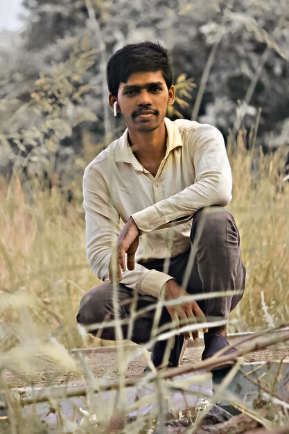 Photo portrait d'un jeune homme accroupi sur la terre ferme