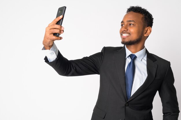 Portrait de jeune homme d'affaires africain beau en costume contre le mur blanc