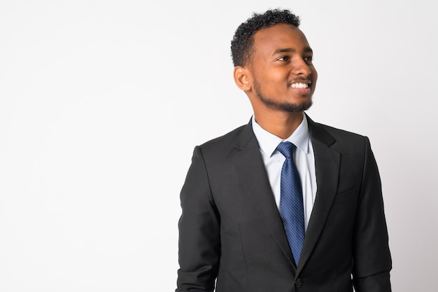 Portrait de jeune homme d'affaires africain beau en costume contre le mur blanc