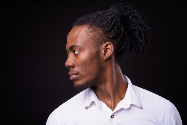 Portrait de jeune homme d'affaires africain beau avec des dreadlocks sur fond noir