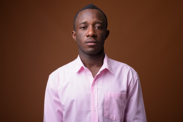 Portrait de jeune homme d'affaires africain contre le mur marron