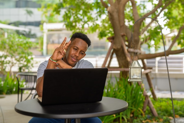 Portrait de jeune homme d'affaires africain portant des vêtements décontractés et assis au café