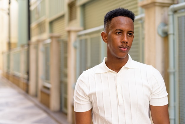 Portrait de jeune homme d'affaires africain portant des vêtements décontractés dans la rue de la ville tout en pensant