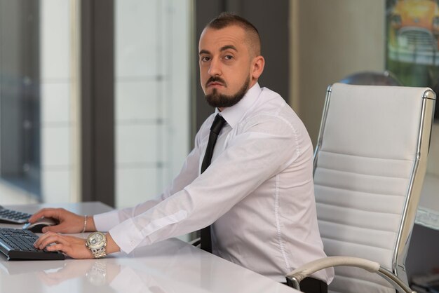 Portrait d'un jeune homme d'affaires à l'aide d'un ordinateur au bureau