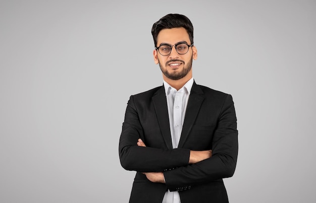 Portrait d'un jeune homme d'affaires arabe confiant dans des lunettes debout avec les bras croisés