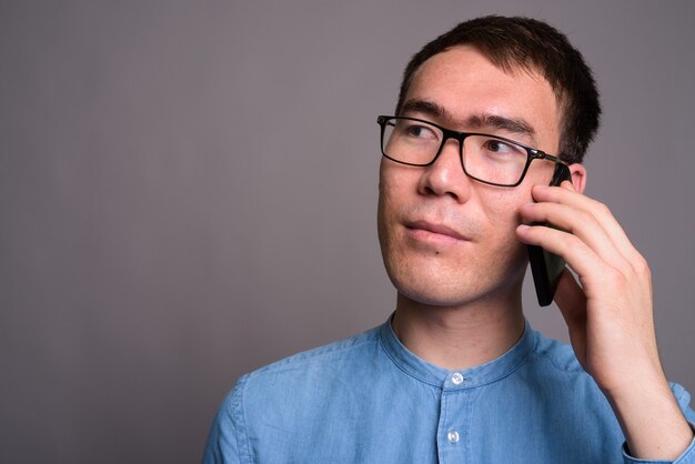 Portrait de jeune homme d'affaires asiatique contre le mur gris