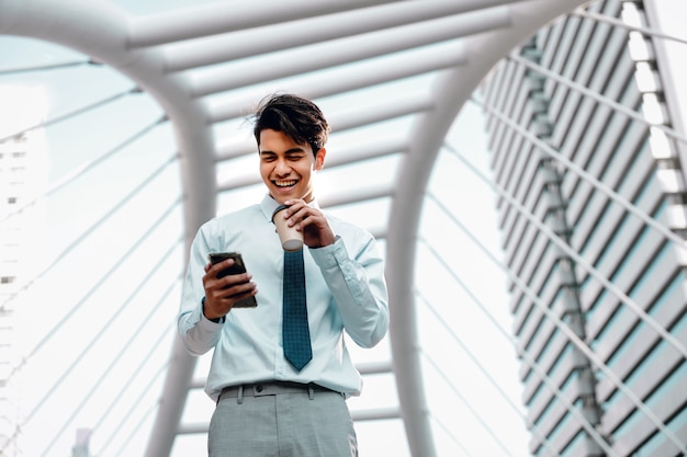 Portrait D'un Jeune Homme D'affaires Asiatique Souriant à L'aide De Téléphone Portable Dans La Ville