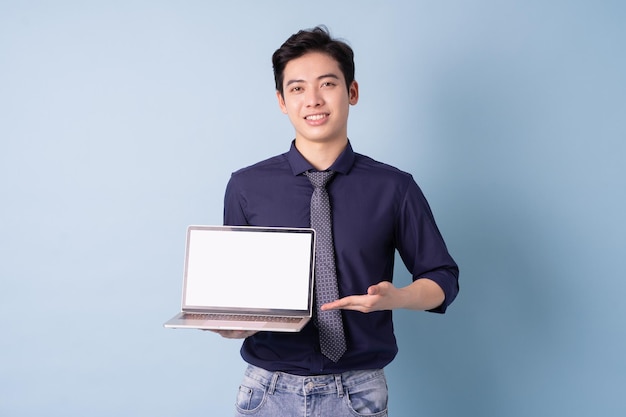 Portrait de jeune homme d'affaires asiatique utilisant un ordinateur portable sur fond bleu