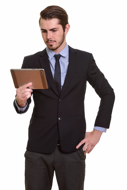 Portrait de jeune homme d'affaires barbu beau en costume à l'aide de tablette numérique