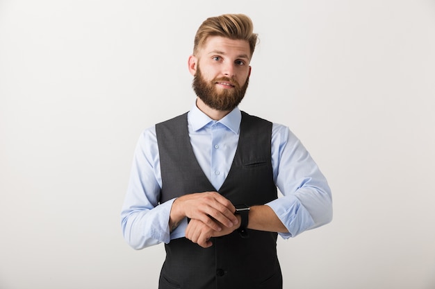 Portrait d'un jeune homme d'affaires barbu confiant debout isolé sur un mur blanc, portant une montre intelligente