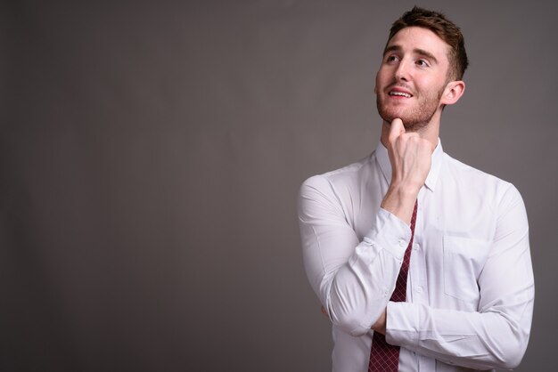 Portrait de jeune homme d'affaires beau contre gris