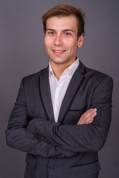 Portrait de jeune homme d'affaires beau contre le mur gris