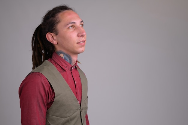 Portrait de jeune homme d'affaires beau avec des dreadlocks contre un mur blanc