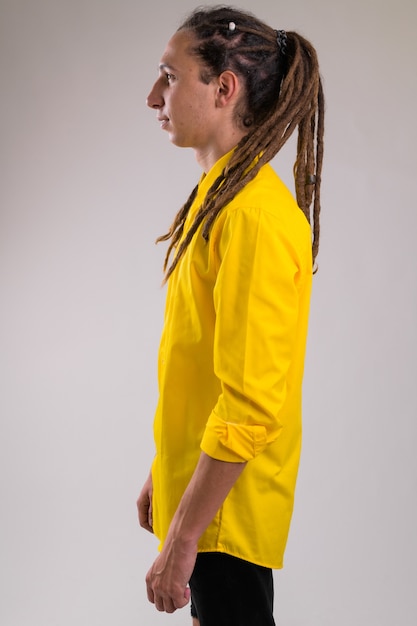 Portrait de jeune homme d'affaires beau avec des dreadlocks contre un mur blanc