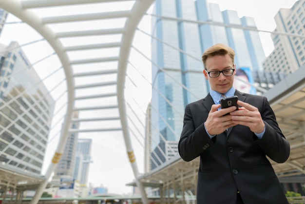 Portrait de jeune homme d'affaires blond beau en costume au pont de skywalk dans la ville en plein air