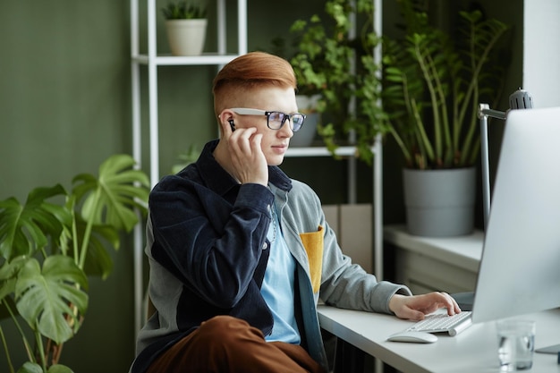 Portrait d'un jeune homme d'affaires branché utilisant un ordinateur tout en travaillant au bureau dans un bureau vert