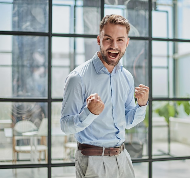 Photo portrait d'un jeune homme d'affaires dans une chemise bleue secouant ses poings célébrant son succès