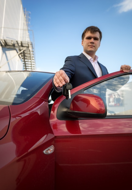 Portrait de jeune homme d'affaires heureux montrant de nouvelles clés de voiture