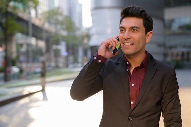 Portrait de jeune homme d'affaires hispanique beau à l'extérieur de l'immeuble de bureaux
