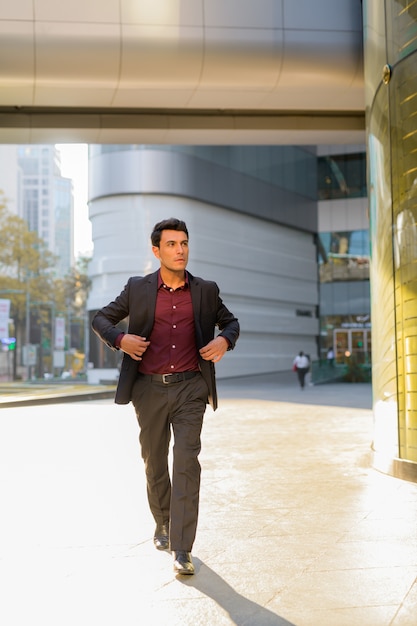 Portrait de jeune homme d'affaires hispanique beau à l'extérieur de l'immeuble de bureaux