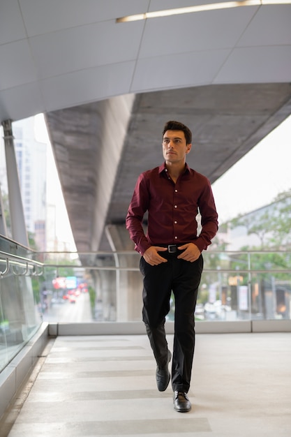 Portrait de jeune homme d'affaires hispanique beau sur la passerelle de la ville