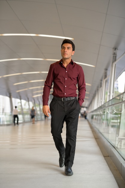 Portrait de jeune homme d'affaires hispanique beau sur la passerelle de la ville